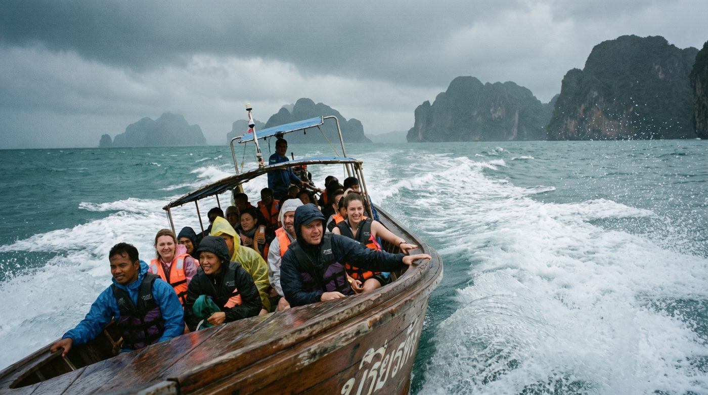 Small Thai speedboat bouncing through choppy Andaman Sea waves near limestone cliffs