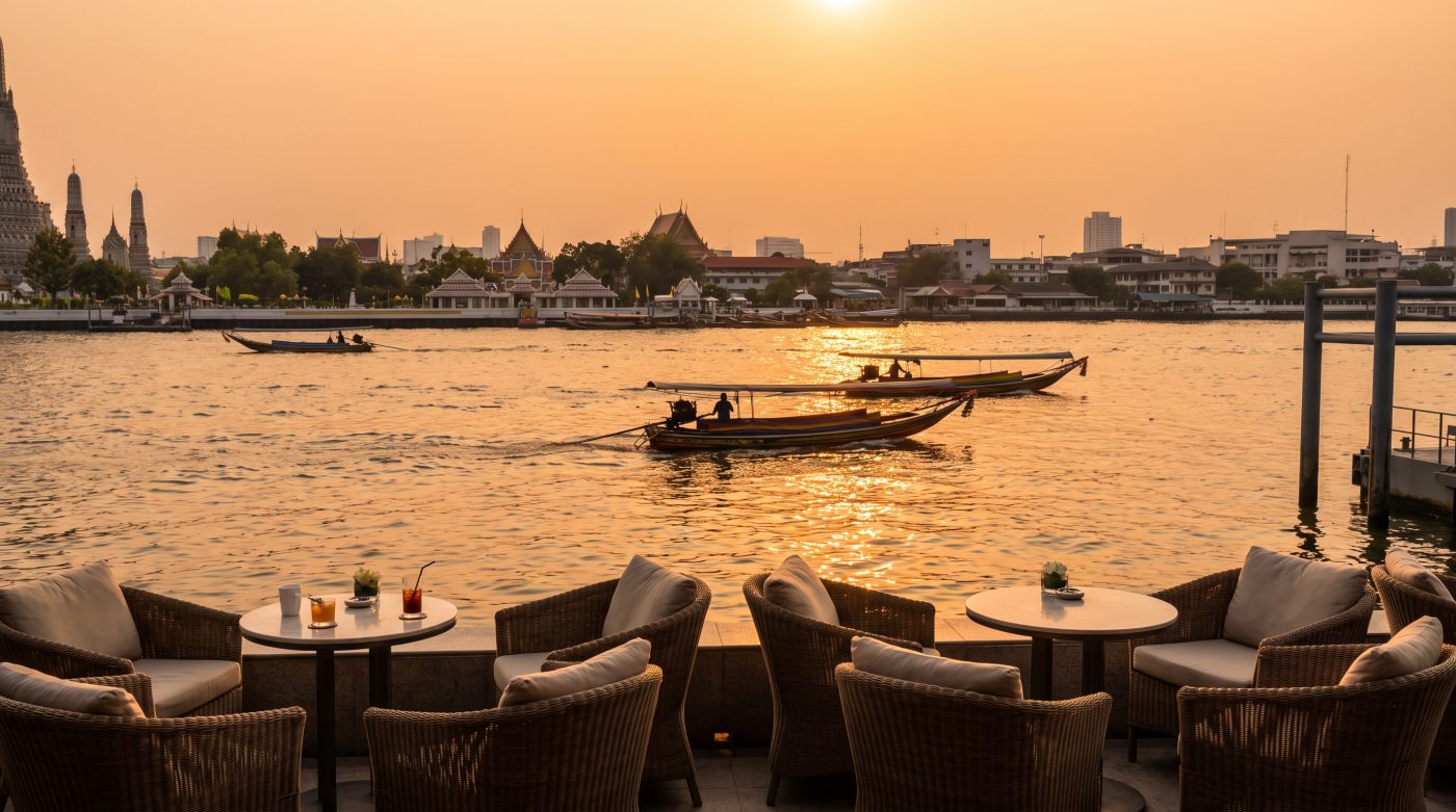 Chao Phraya river at sunset in Bangkok with a riverside terrace and long-tail boats