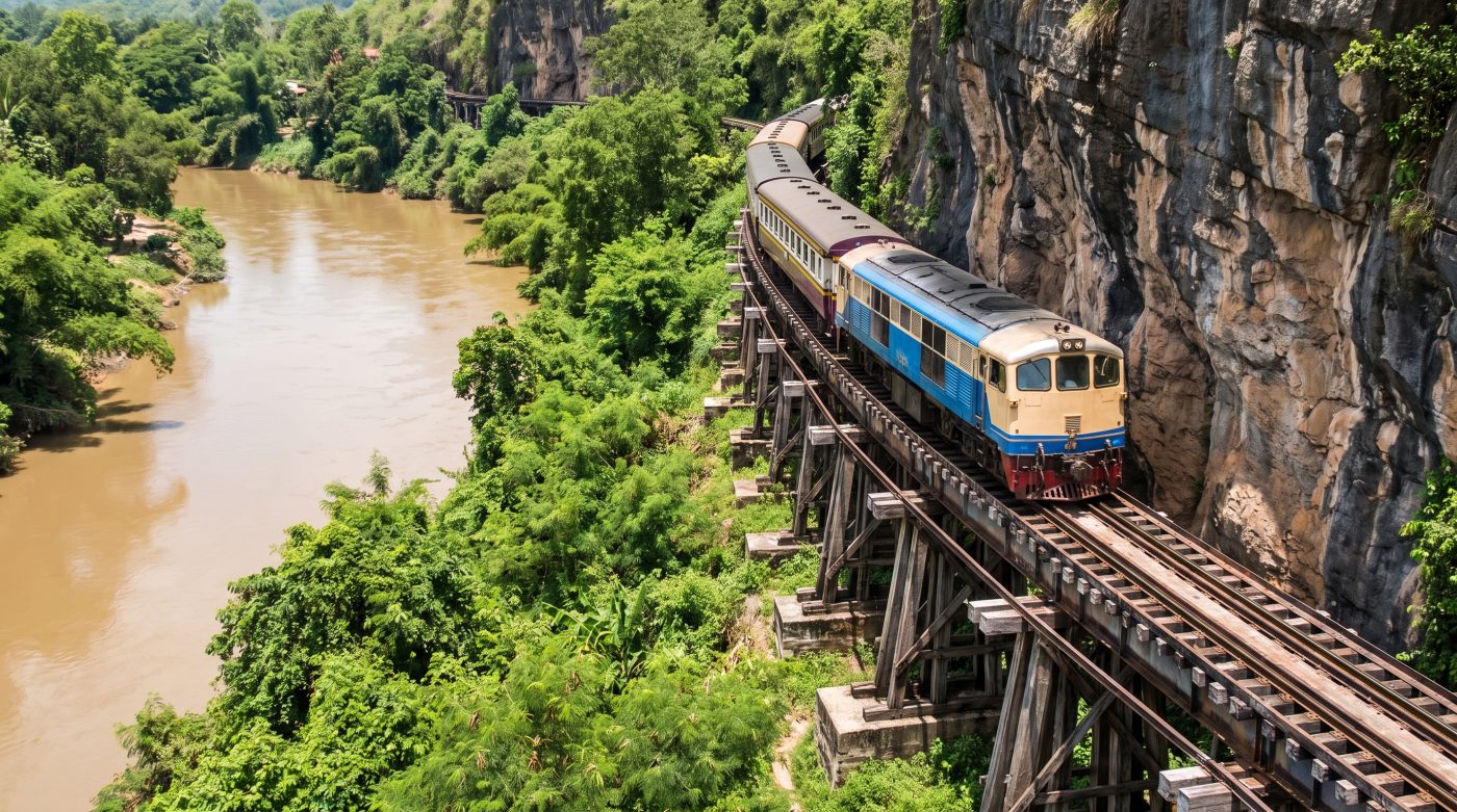 A train crossing the wooden Wang Pho viaduct on the Death Railway, built along a limestone cliff face above the river