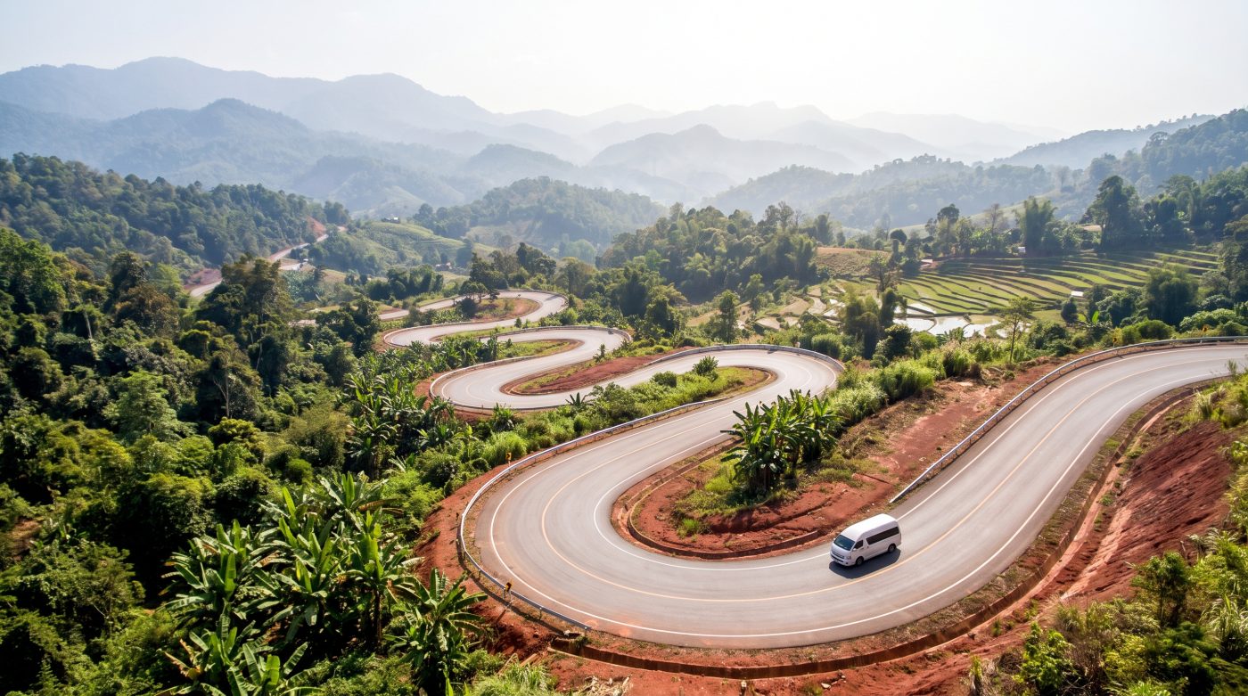 Winding mountain road with hairpin curves through green hills on the way to Pai