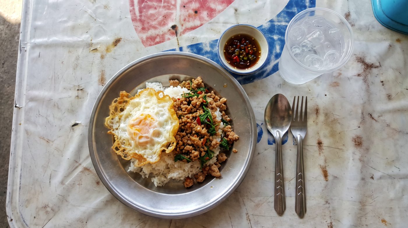 Plate of pad krapow with fried egg on a street-side table in Pattaya