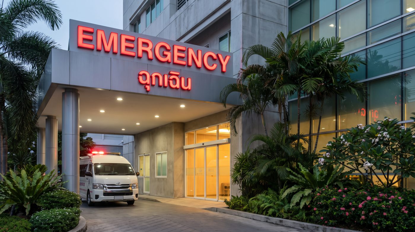 Private hospital emergency entrance with illuminated Emergency sign in Thailand