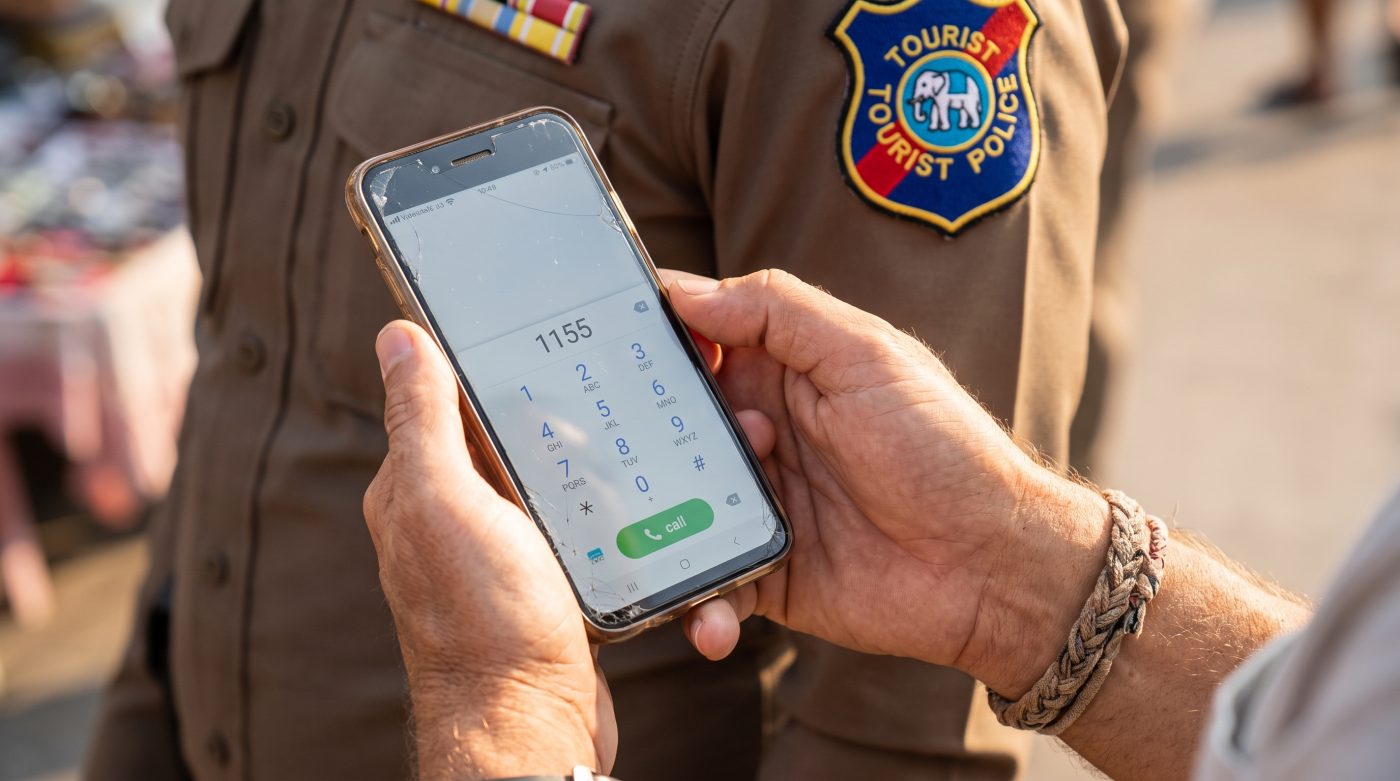 Tourist dialing the Thailand Tourist Police number 1155 on a smartphone